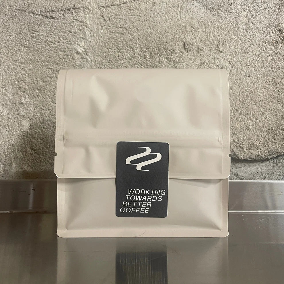 Dos du sachet de café Tribute avec le logo Working Towards Better Coffee