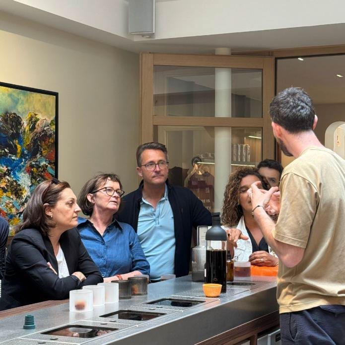 Un groupe goûte des cafés autour du comptoir, guidé par un barista