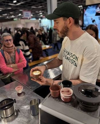 Un barista prépare un café devant le public d’un salon