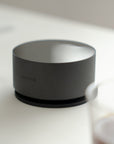 Acaia Horizon posé sur son tapis en silicone à côté d’un verre de café filtre