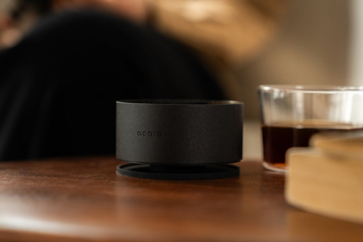 Acaia Horizon sur une table en bois à côté d’un verre de café filtre