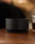 Acaia Horizon sur une table en bois à côté d’un verre de café filtre
