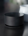 Acaia Horizon en aluminium anodisé noir à côté d’une tasse en céramique